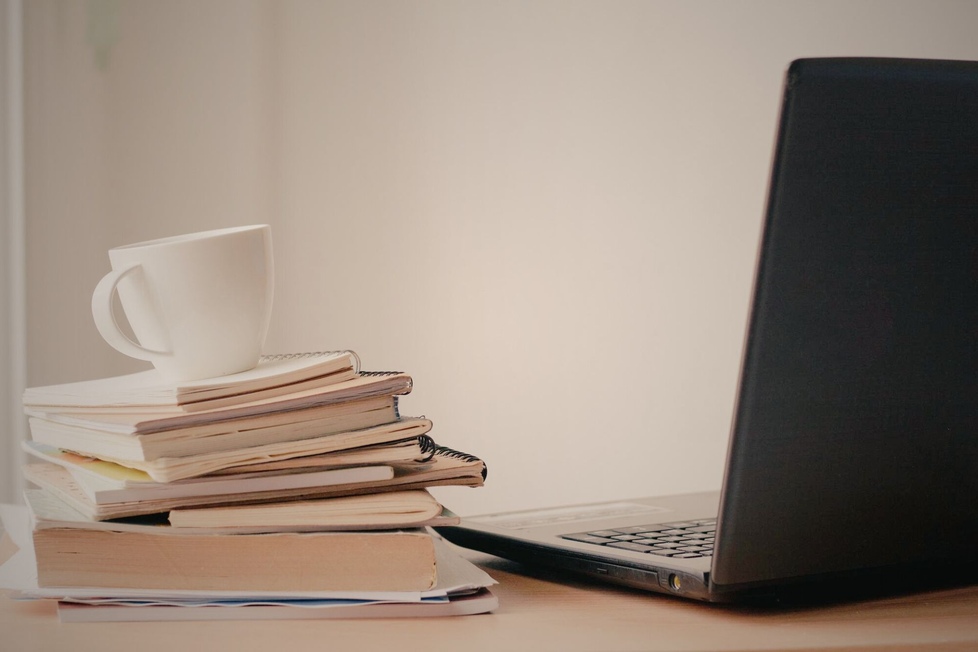 A stack of books next to an open laptop computer